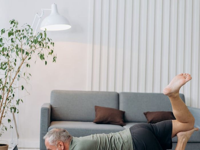 Man stretching on a yoga mat in a modern, sunlit room, focusing on flexibility.